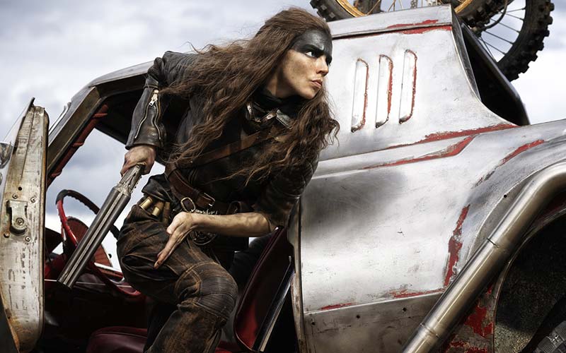 Furiosa getting out of a war vehicle armed with a shotgun