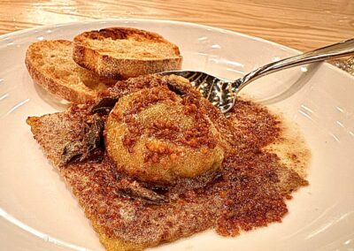 a single, large egg yold raviolo with two pices of foccacia toast