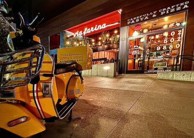 A shot of Via Farina from the outside at night with the yellow delivery scooter in the foreground