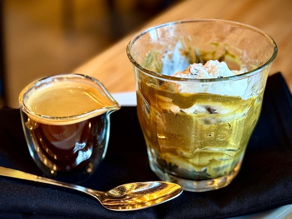 a shot of espresso next to a glass with pistachio gelato as an affogato dessert