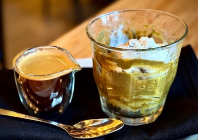 a shot of espresso next to a glass with pistachio gelato as an affogato dessert