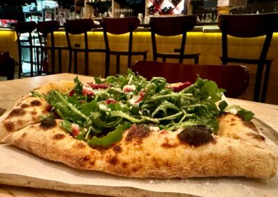 a pizza topped with arugula, sausage, roasted peppers, the salciccia