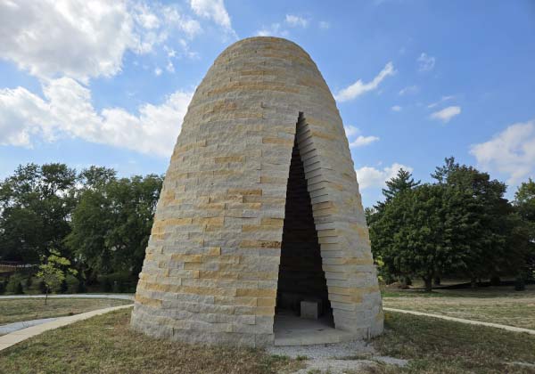 This tipi-like structure is made of stone and has a fire pit and bench seating inside. It's part of a linear park along the west side of Heartwood Preserve