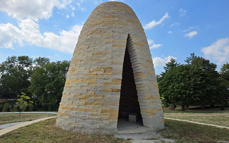 This tipi-like structure is made of stone and has a fire pit and bench seating inside. It's part of a linear park along the west side of Heartwood Preserve