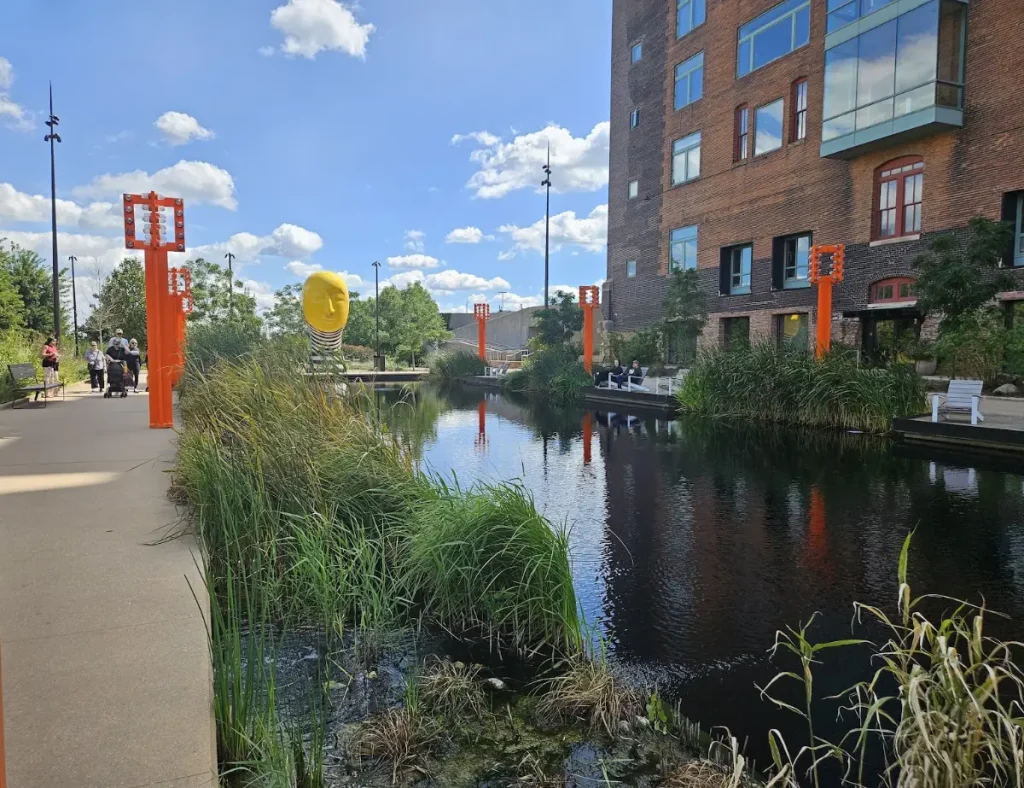 Looking east from inside the renovated Gene Leahy Mall with the pond in the middle, the Greenhouse apartments to the right, and one of several sculptures on display in the park. This bronze sculpture from Jun Kaneko is titled Dream.
